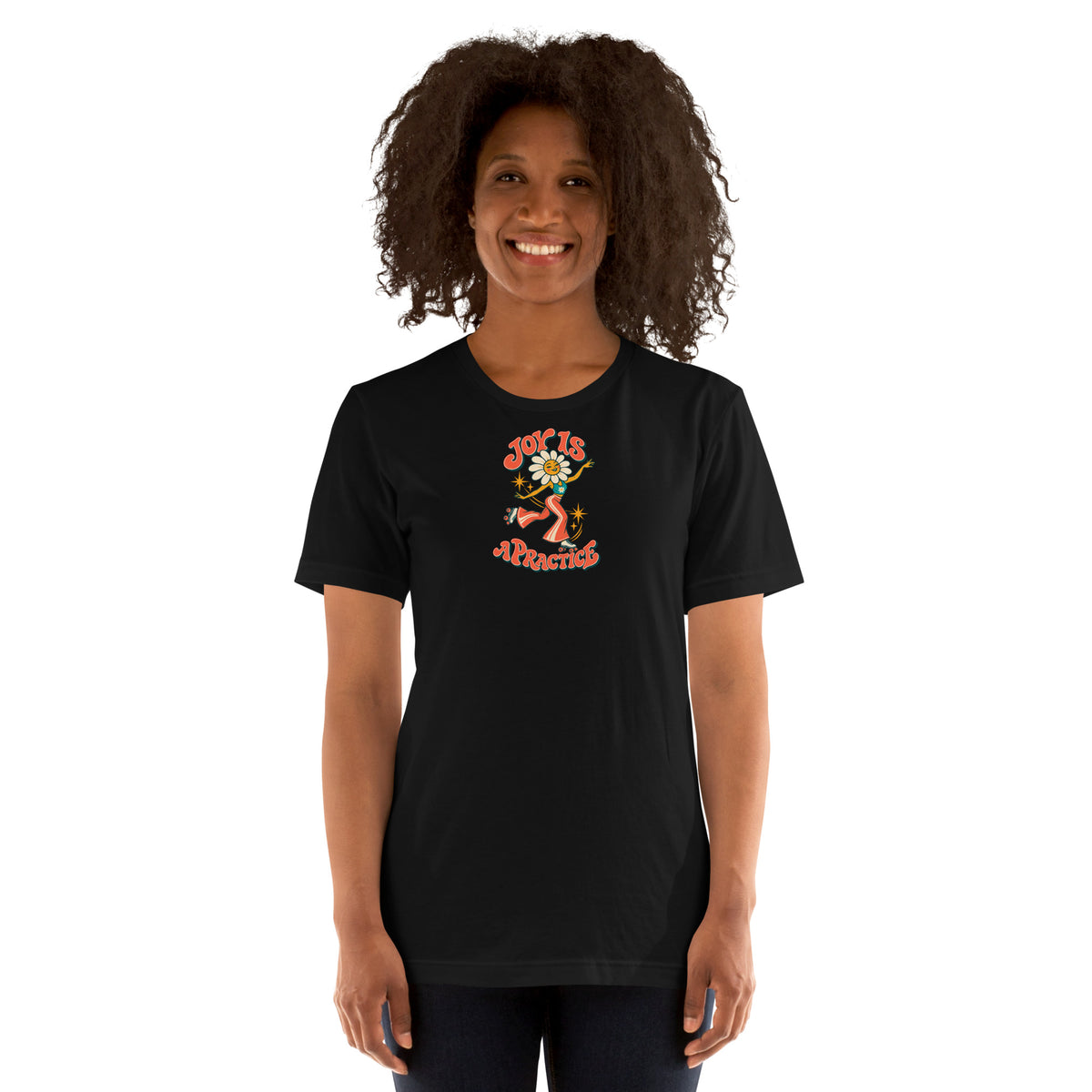 Woman modeling a black Joy Is a Practice t-shirt with a flower-headed roller skater and colorful retro lettering on the front.