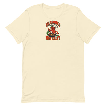 Front of a Natural Seasoned, Not Salty graphic T-shirt with a red chili-pepper chef stirring a skillet.