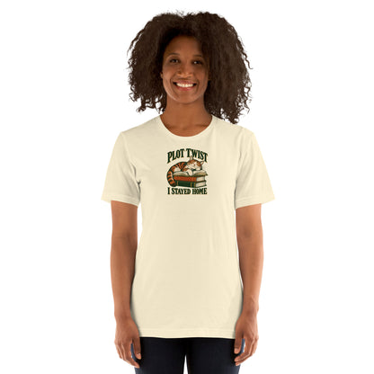 Model wearing the Natural cream Plot Twist I Stayed Home T-shirt with cat-and-books artwork on the front.